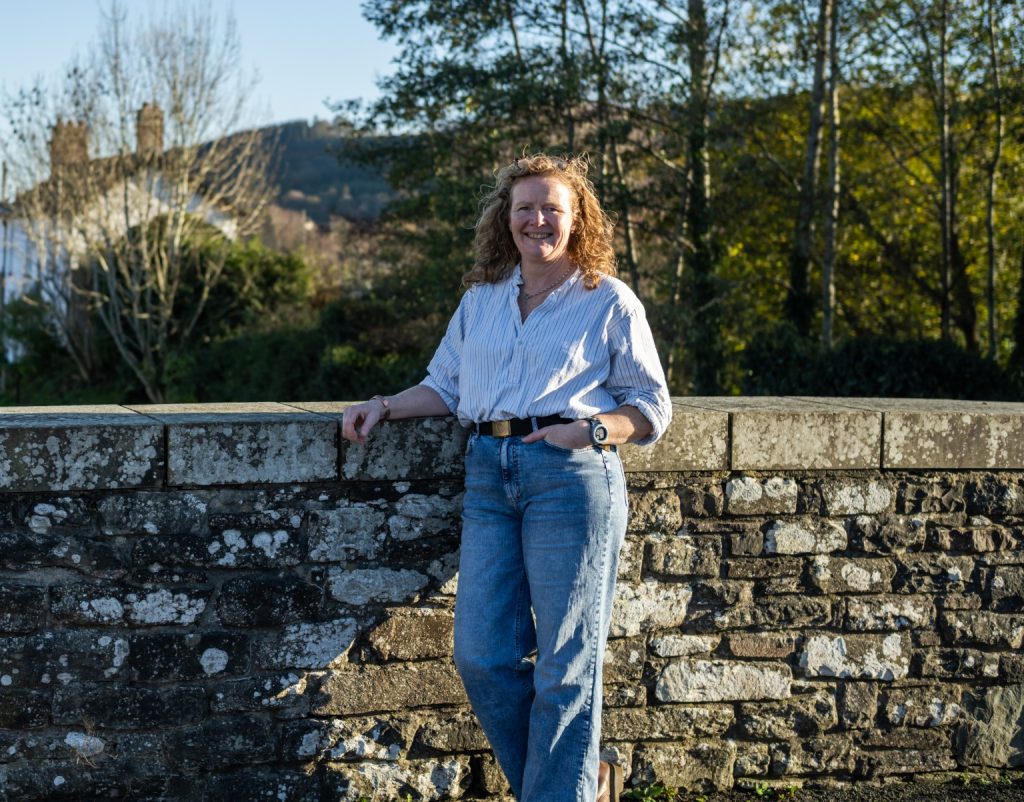 Julie Bell standing beside a stone wall outdoors