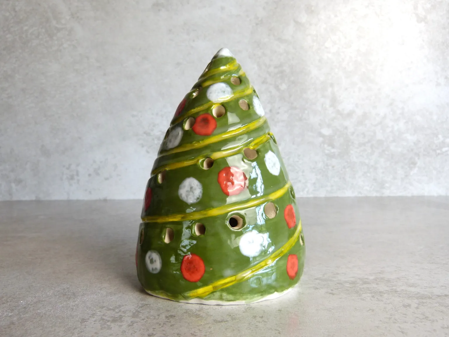 Handmade green ceramic Christmas tree lantern decorated with red and white baubles