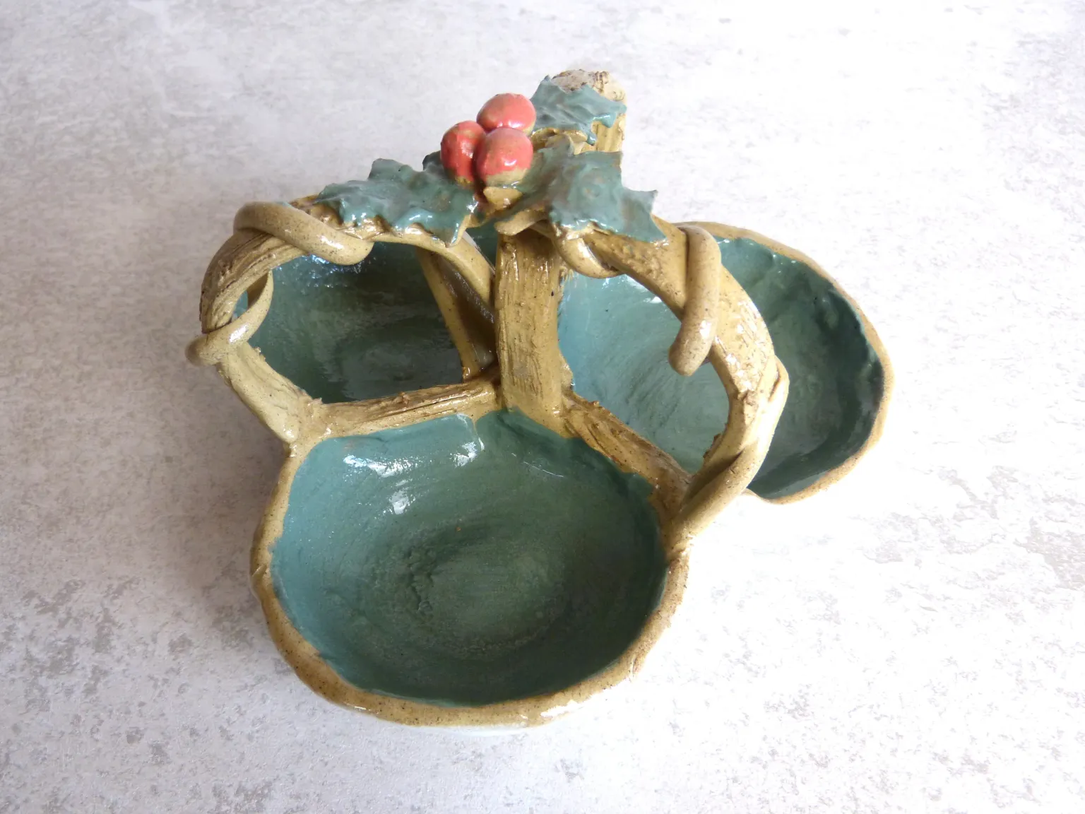 Three handmade ceramic snack bowls joined by branches and decorated with holly