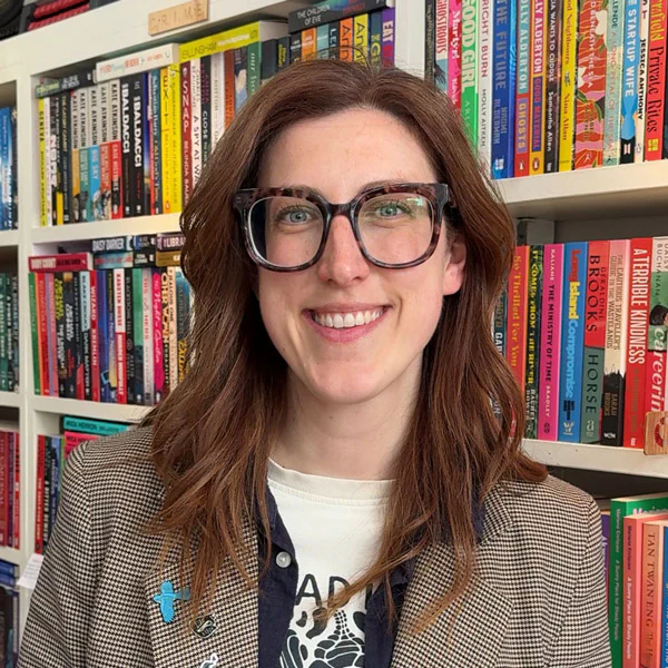 A smiling member of the Book-ish team in front of bookshelves