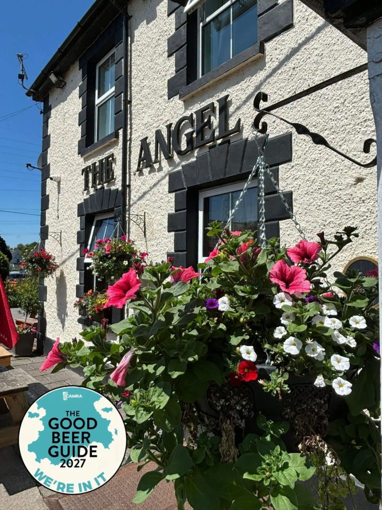 The Angel Inn at Pontneddfechan with a CAMRA Good Beer Guide 2027 sign and colourful hanging flowers.