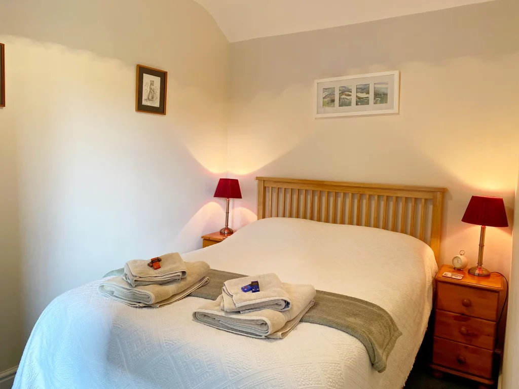 Double bedroom with a wooden bed and bedside tables at Aberyscir Coach House