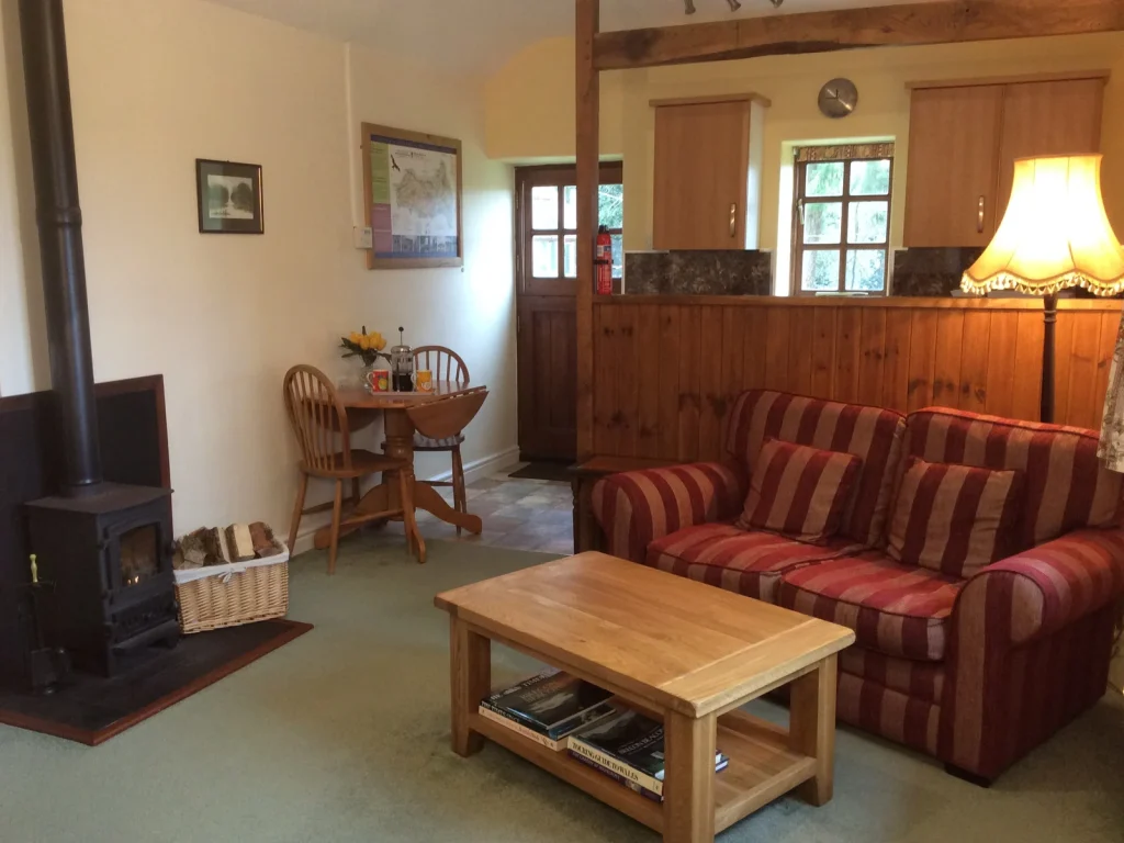 Lounge with a sofa, wood-burning stove and kitchen at Aberyscir Coach House