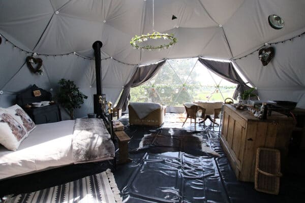 Bed, dining area and kitchen inside the Seren Bach glamping dome at Argoed Barns