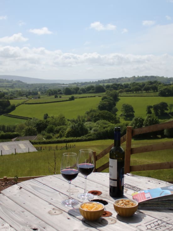 Wine and snacks on a table overlooking fields and hills from Seren Mawr at Argoed Barns