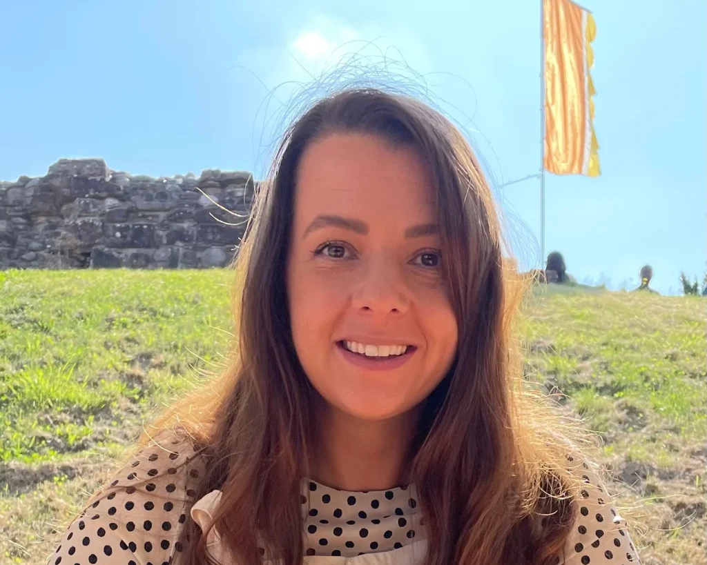 Sarah from Bannau Creative smiling outdoors beside a stone ruin