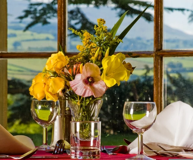 Table with flowers and drinks beside a window overlooking the Wye Valley