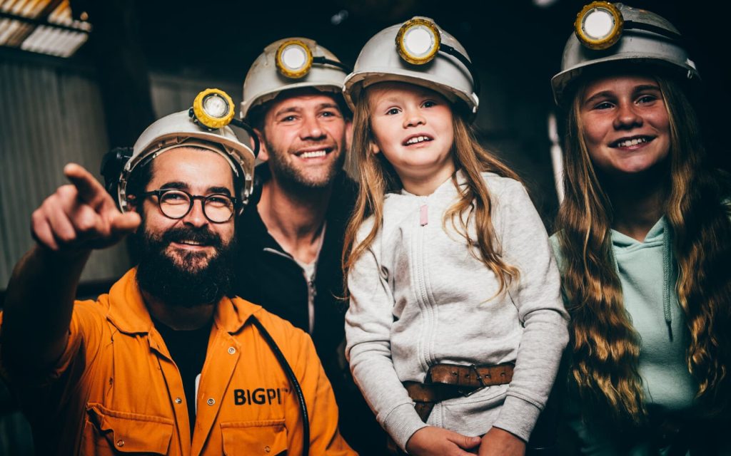 Family wearing miners’ helmets during a visit to Big Pit National Coal Museum