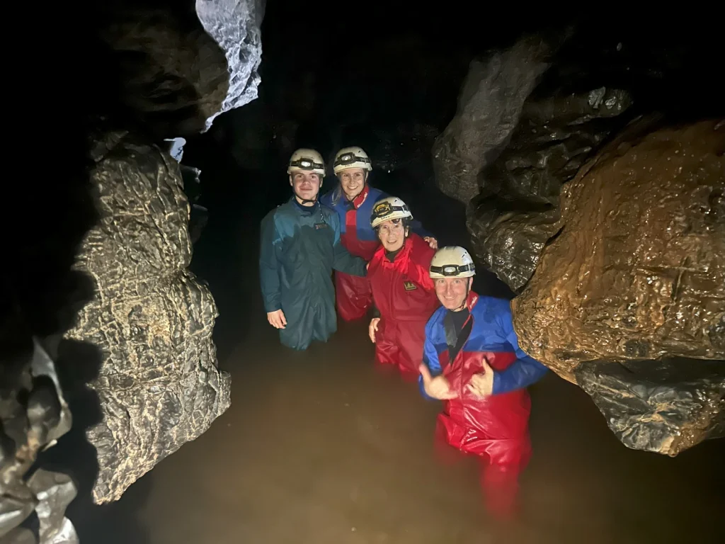 Group wearing helmets while exploring a cave with Black Mountain Adventure