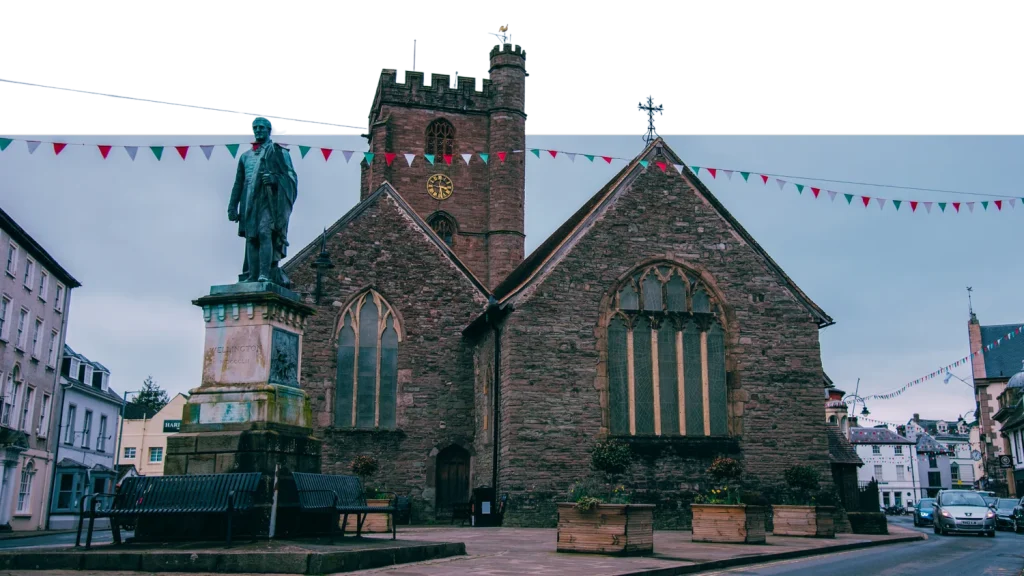 Historic church and statue in Brecon town centre at dusk