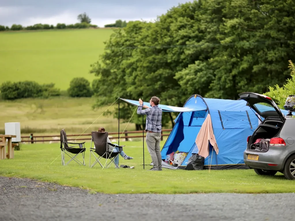 Family tent and car on a grass pitch at Bryndu Caravan and Camping Park