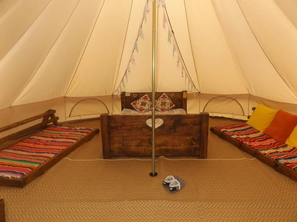 Cushioned sleeping area inside a canvas tipi at Camp Cynrig Glamping Village