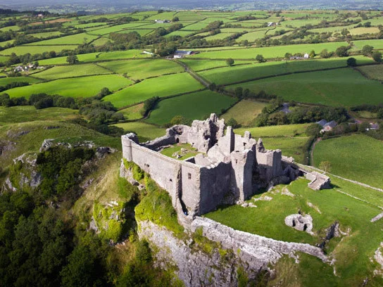 Aerial view of Carreg Cennen Castle on its limestone crag above farmland