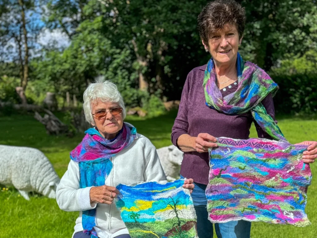 Two women displaying colourful wet-felted landscape artworks from Fabulous Feltings