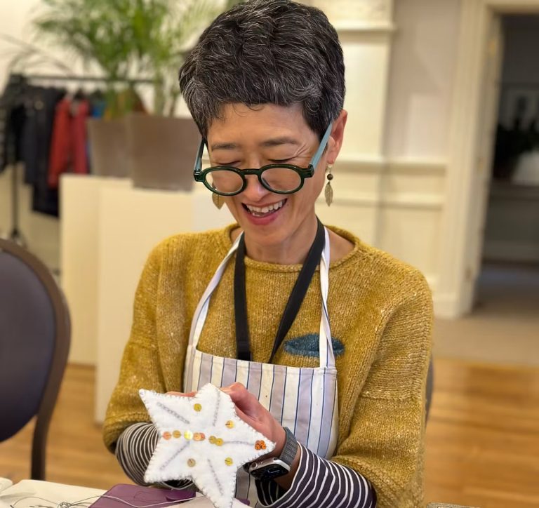 Participant holding a handmade embroidered festive bird during the workshop