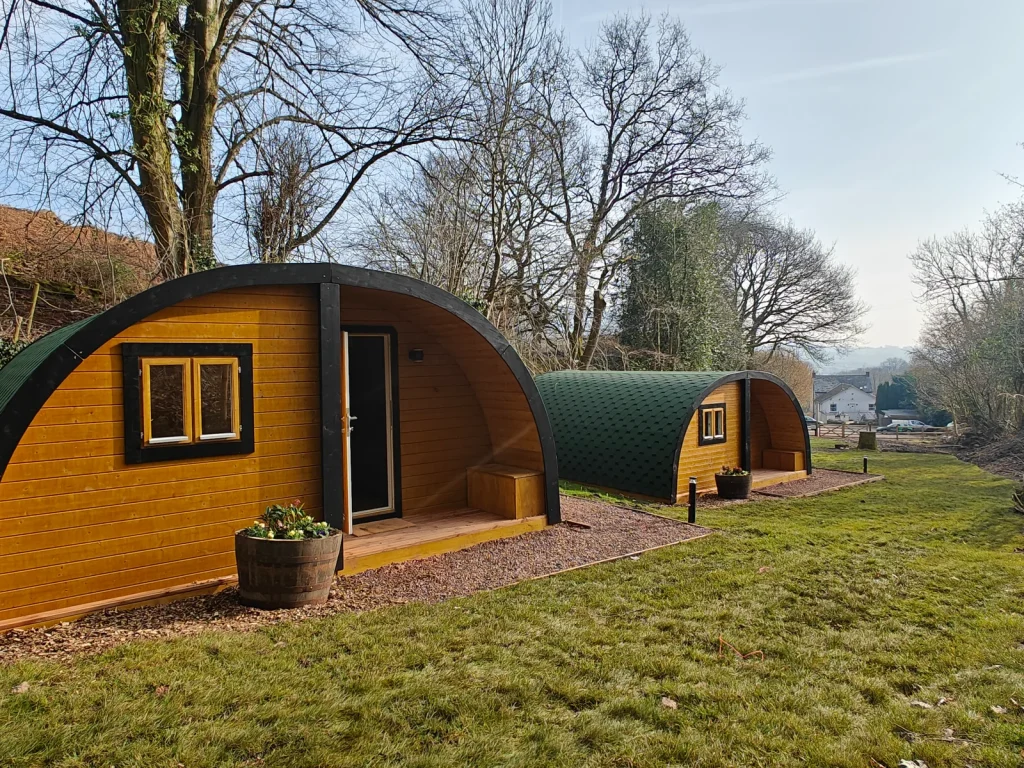 Wooden camping pods in a grassy setting listed by Glampingstays.co.uk