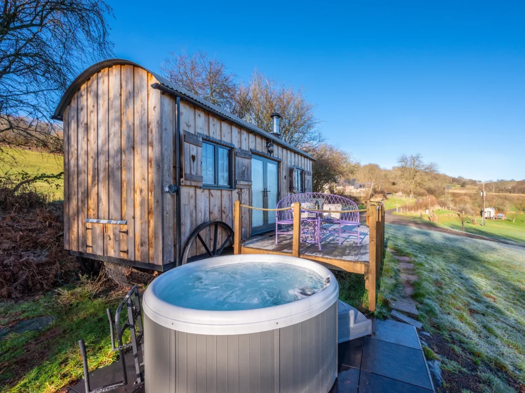 Wooden glamping wagon with an outdoor hot tub listed by Glampingstays.co.uk