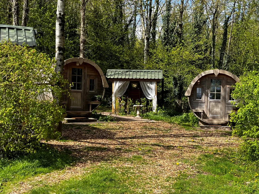 Small wooden huts in a leafy woodland setting listed by Glampingstays.co.uk