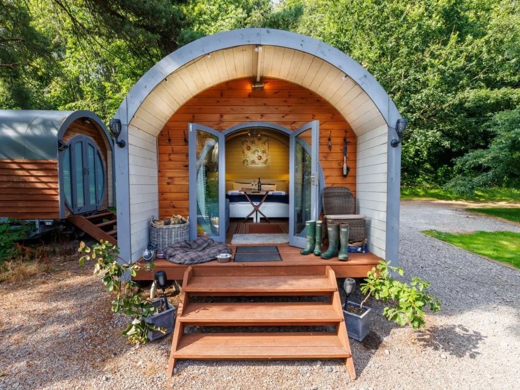 Wooden glamping wagon with steps among trees at Glanusk Estate