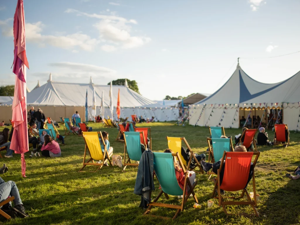 Colourful Festival site with tents, deckchairs and visitors in Hay-on-Wye