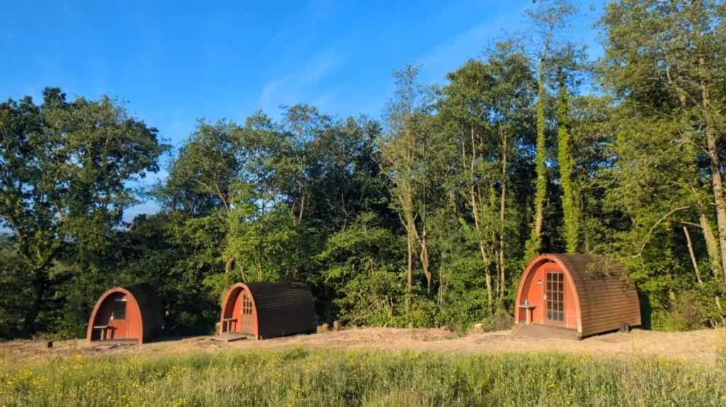 Three timber camping pods in a meadow at Llandyfan Camping and Fishing