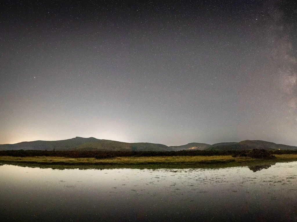 Milky Way above a mountain lake with stars reflected across the water