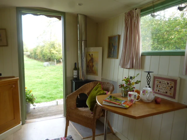 Small table, seating and open door inside a shepherds hut