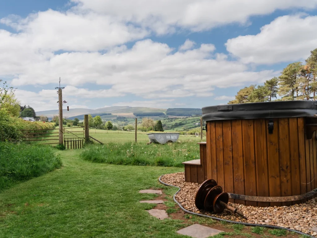 Outdoor wood-fired hot tub overlooking the countryside at Toad and Snail Glamping in Crai