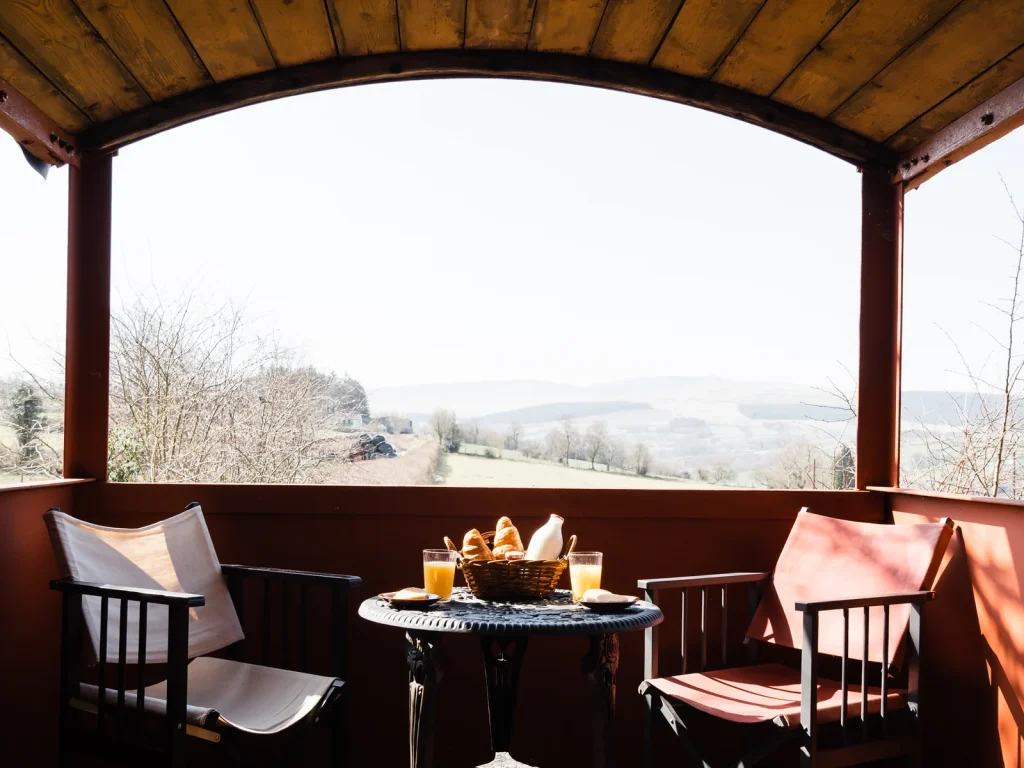 Covered veranda dining space beside a converted wagon at Toad and Snail Glamping