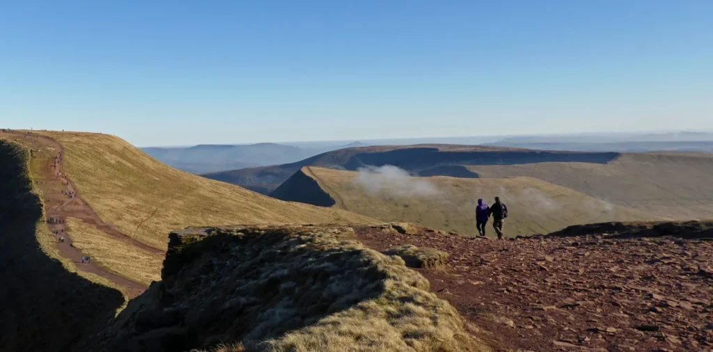 Walkers following a broad mountain ridge in Bannau Brycheiniog