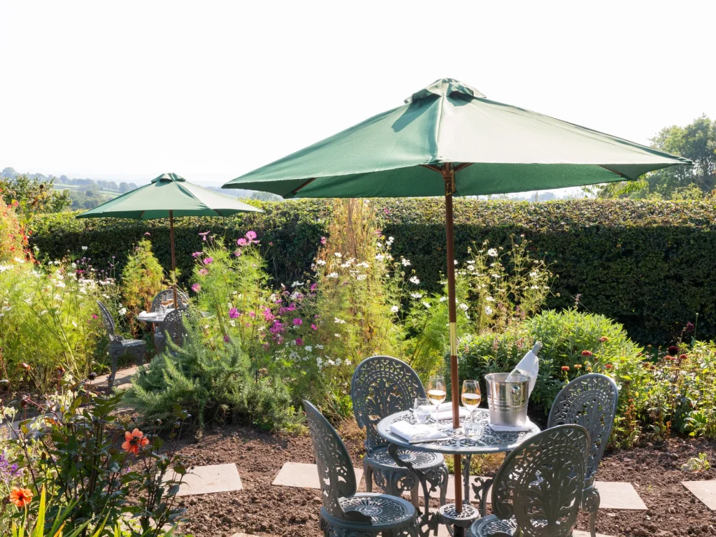 Outdoor tables beneath green parasols in the garden at The Walnut Tree