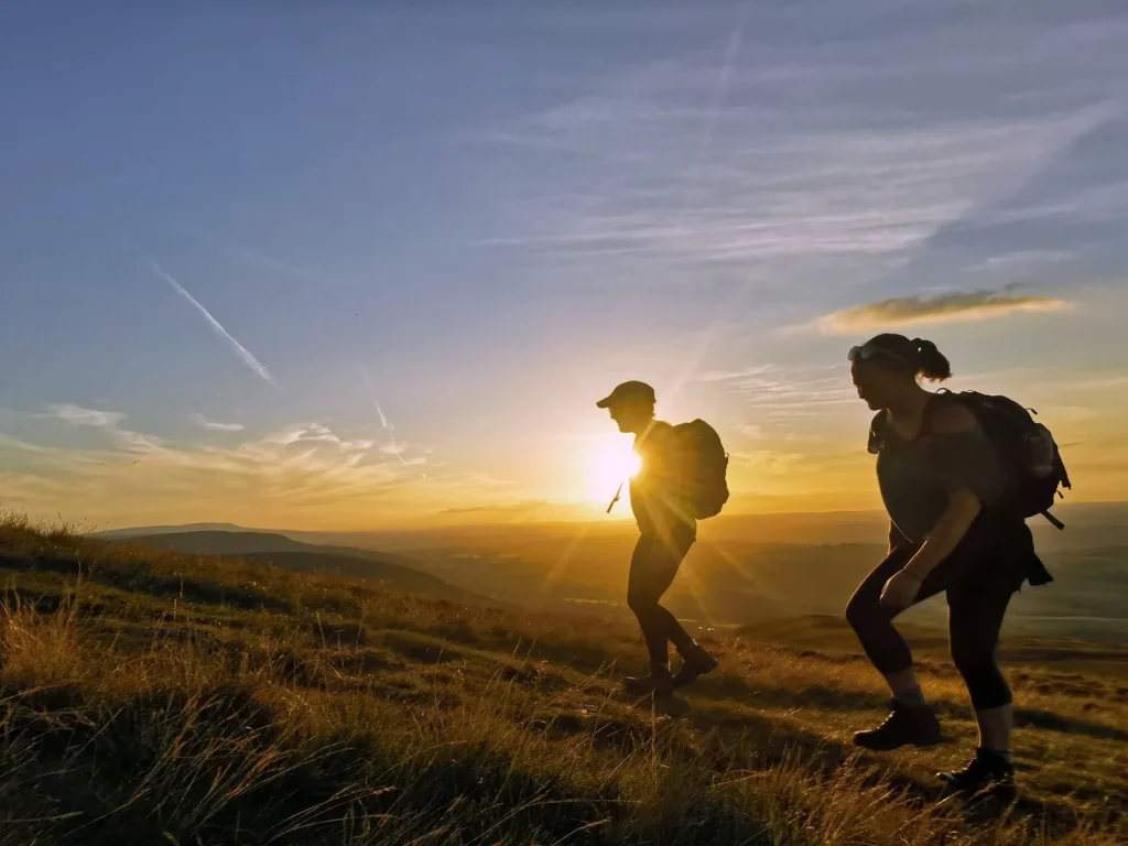 Walkers on open hills at sunrise with Wild Trails Wales
