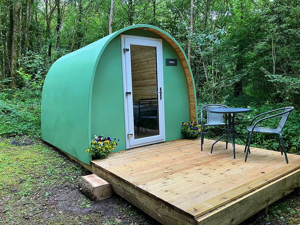 Green Teal glamping pod set among trees at Woodland Park Glamping near Brecon