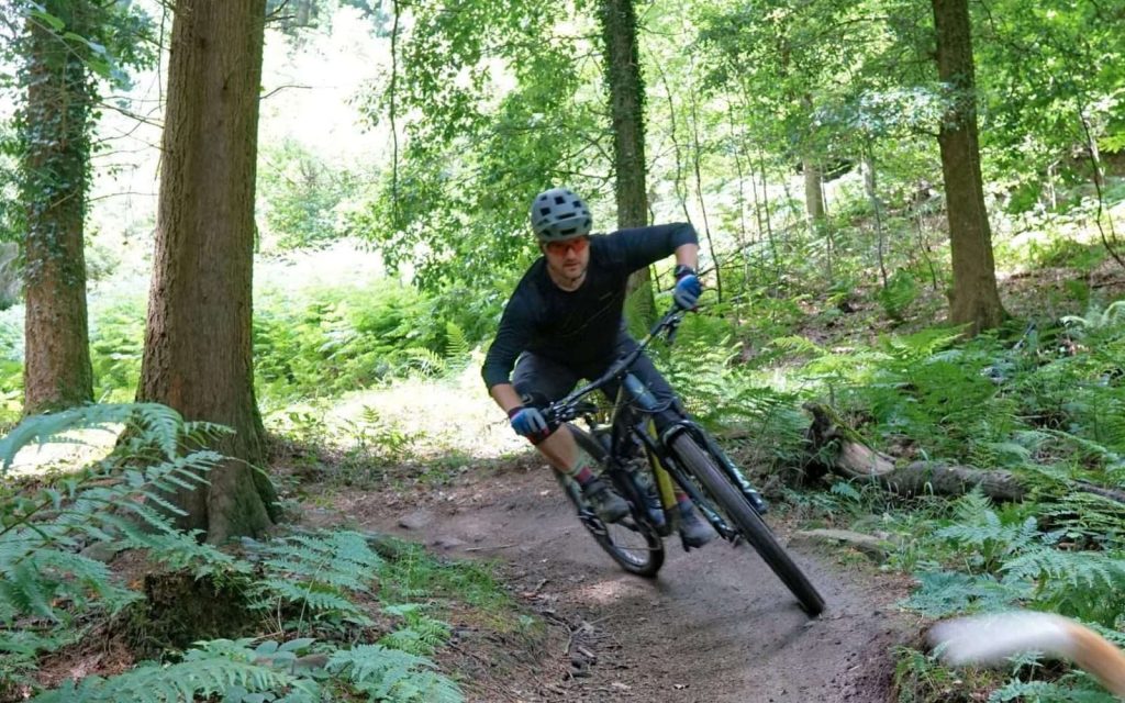 Mountain biker leaning through a wooded trail with Wye MTB