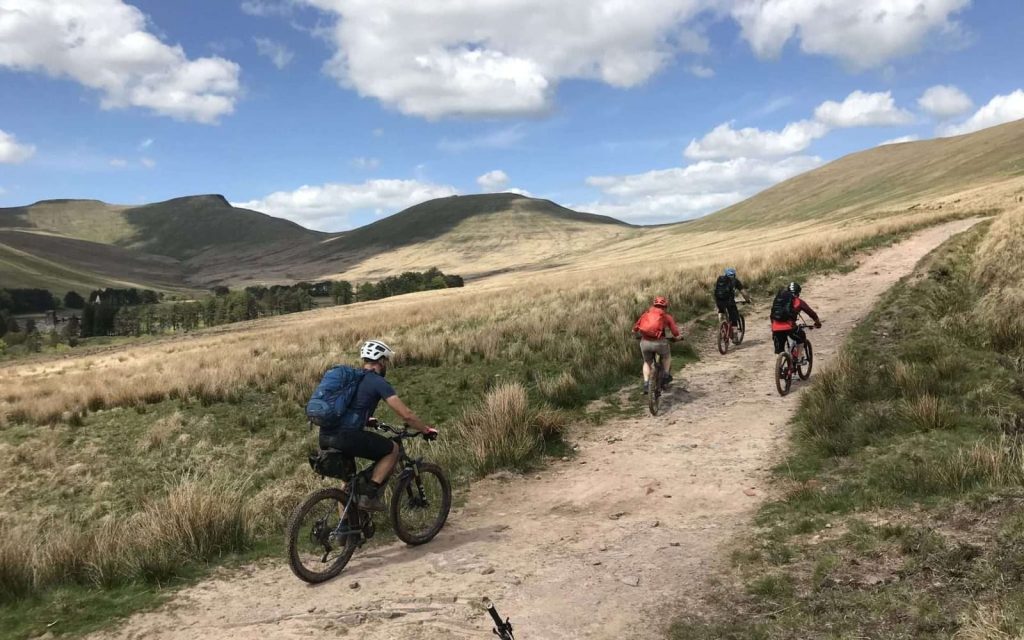 Mountain bikers descending an open upland track in South Wales with Wye MTB