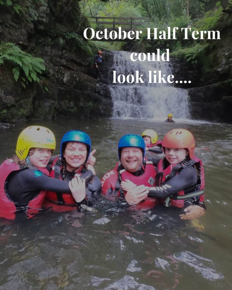 Family group gorge walking beneath a waterfall in Bannau Brycheiniog